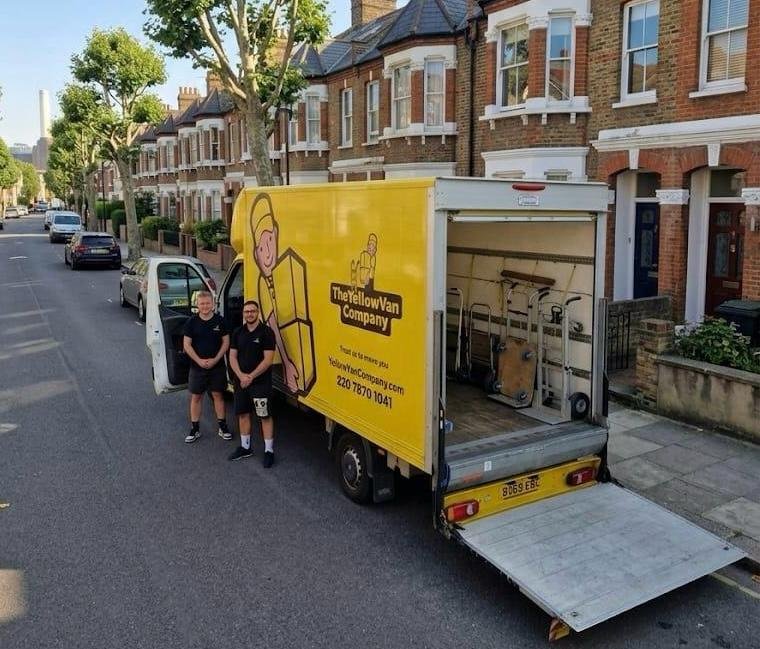 Two uniformed Yellow Van Company movers standing next to an open Luton van loading a residential home move in Battersea SW11 &mdash; family-run London house removals